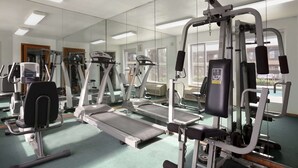 Un gimnasio con cintas de correr, máquinas de pesas y un espejo grande.