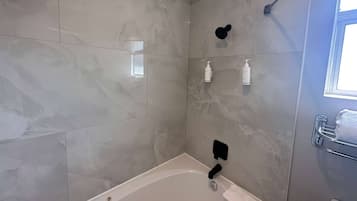 Un baño con bañera, ducha y toallero.