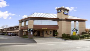 Un hotel Days Inn con fachada marrón, ventanas grandes y un letrero que indica zona de estacionamiento prohibido para camiones.