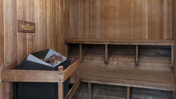 Una sauna de madera con un banco y pared de madera.