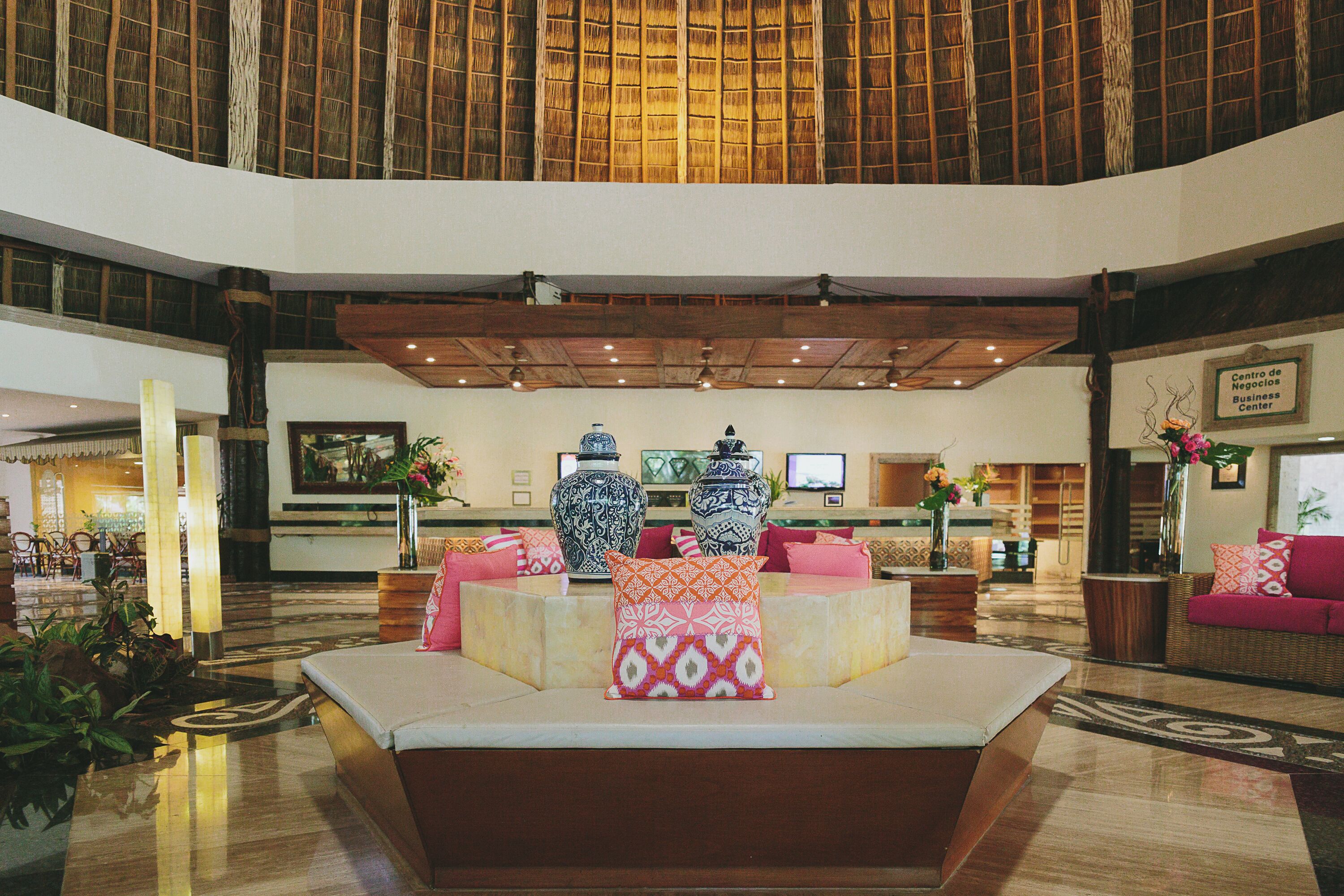 A spacious lobby with a central seating area, large vases, and a reception desk.