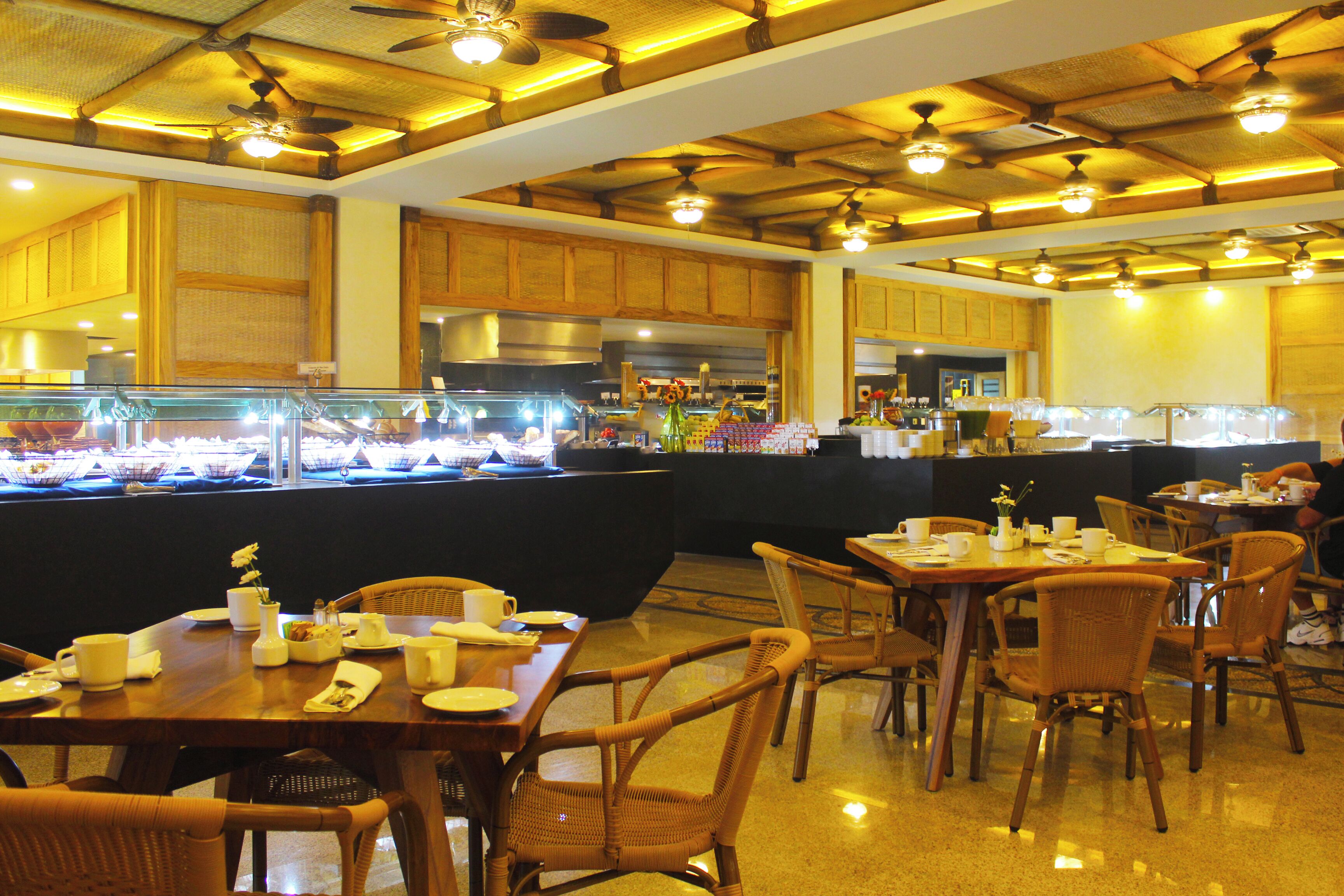 Un restaurante con mobiliario de madera, una mesa de buffet y ventiladores de techo.