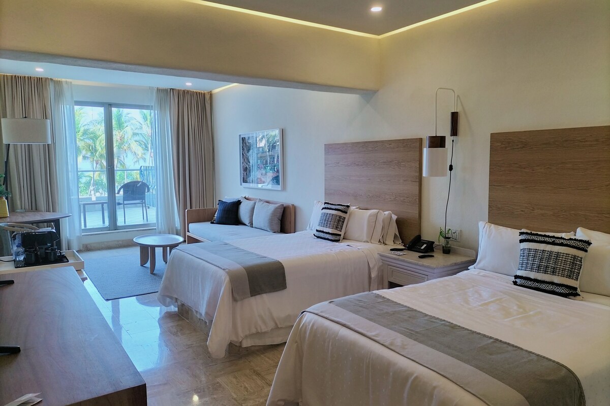 A hotel room with two beds, a desk, a chair, and a large window with curtains.
