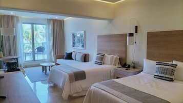 Habitación de hotel con dos camas, un escritorio, una silla y un ventanal con cortinas.
