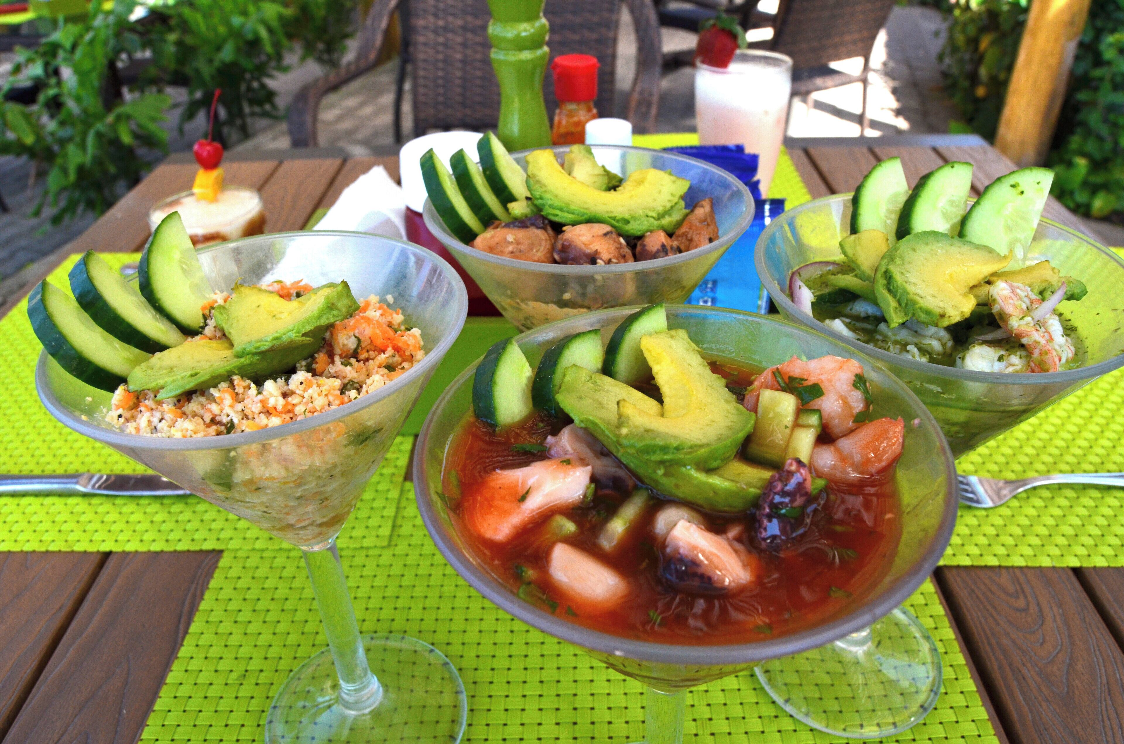 Three bowls of food with avocado and other ingredients on a table.