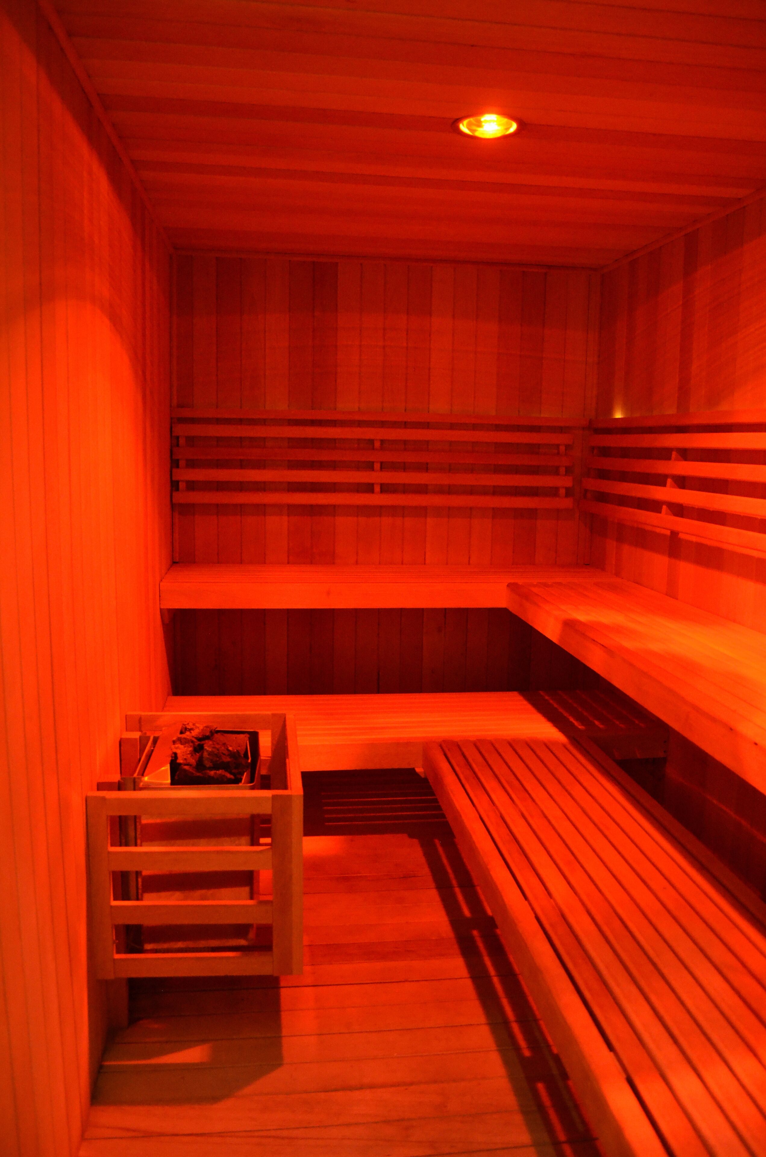 A sauna with wooden benches and a bench with a storage compartment.