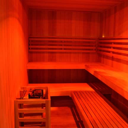 A sauna with wooden benches and a bench with a storage compartment.