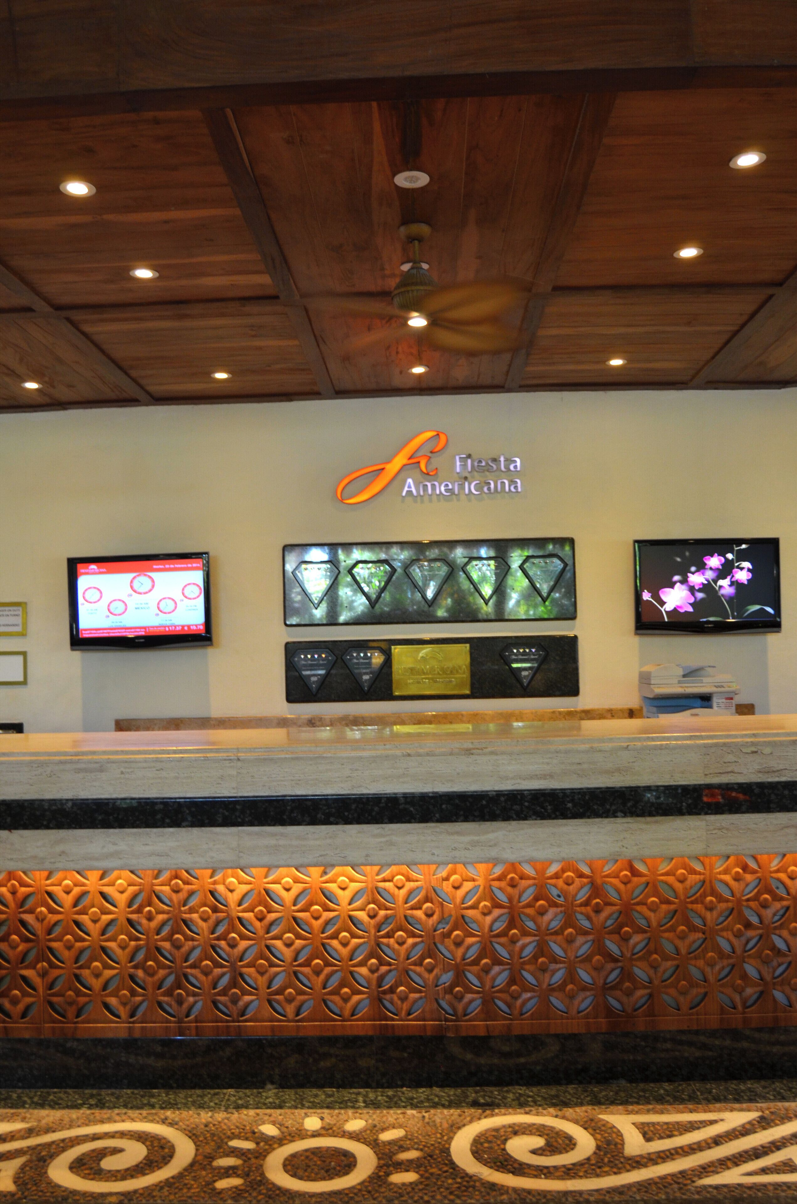 A reception area with a wooden ceiling, a digital display, a wall-mounted TV, and a decorative panel.