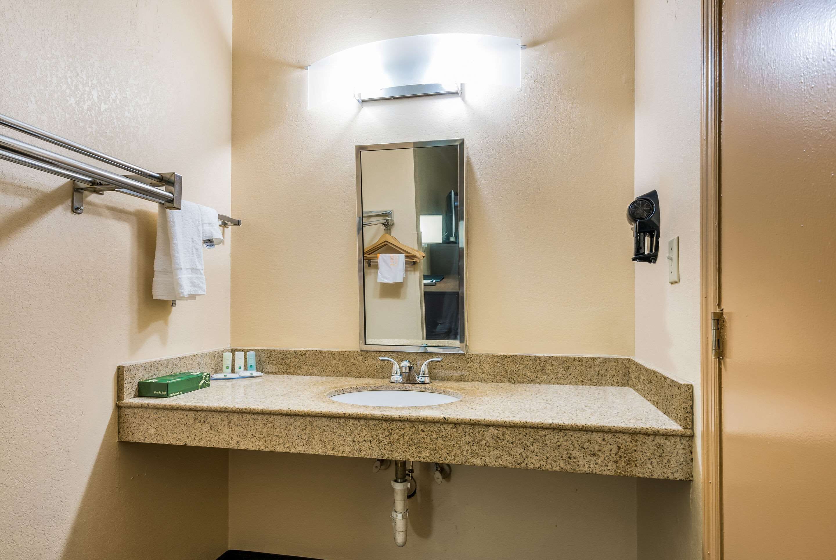 A bathroom with a granite countertop sink, a mirror, a towel rack, and a towel hanging on it.