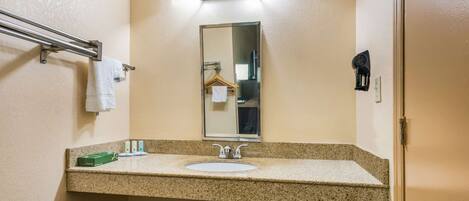 A bathroom with a granite countertop sink, a mirror, a towel rack, and a towel hanging on it.
