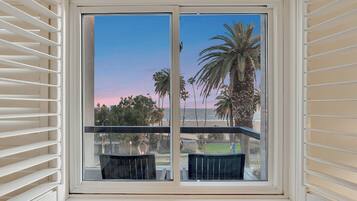 A balcony with a view of palm trees and a sunset.