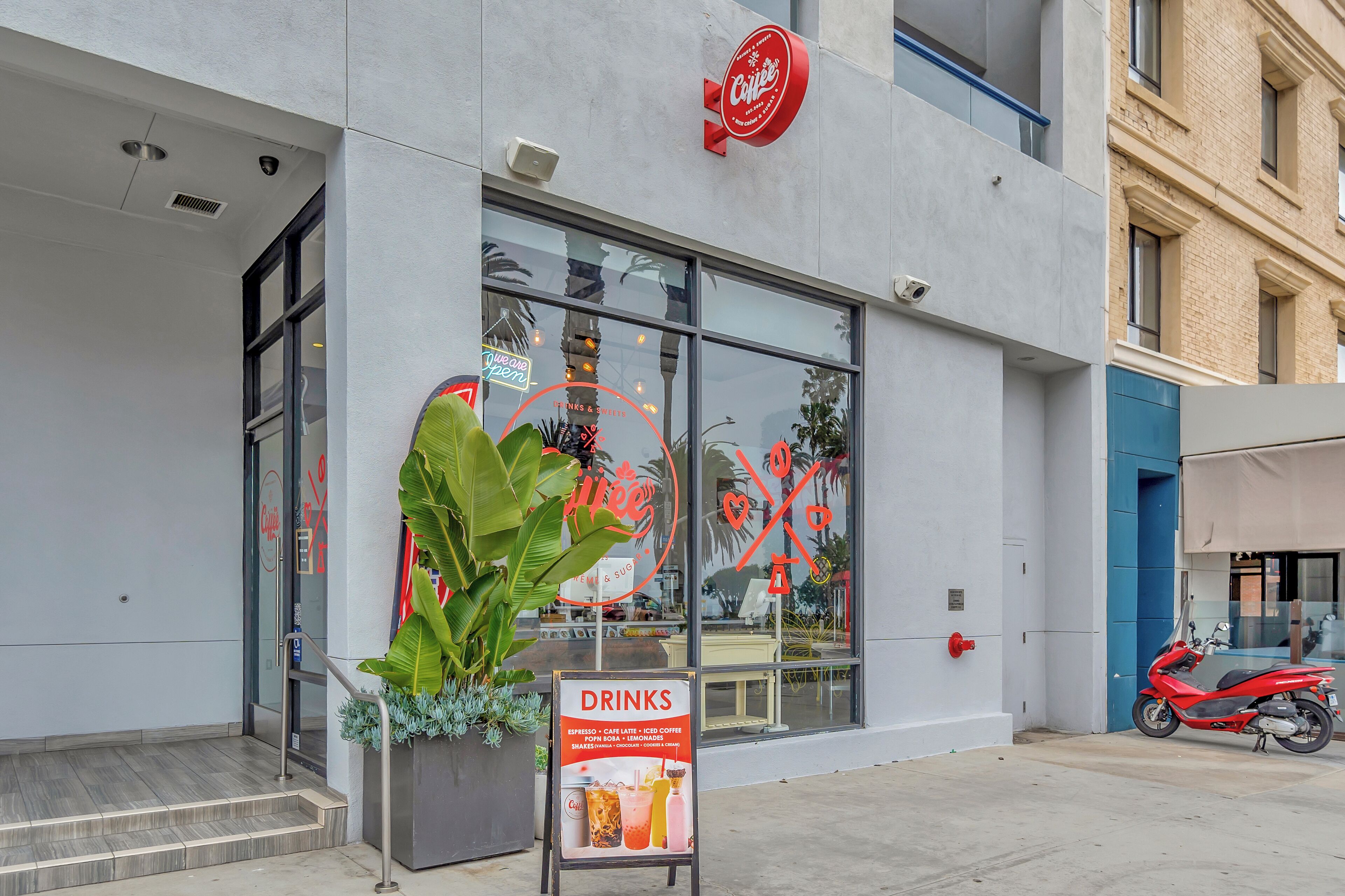 A modern building with a large glass window and a signboard advertising drinks.