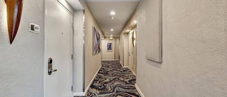 A hallway with a patterned carpet, white walls, and doors numbered 405.