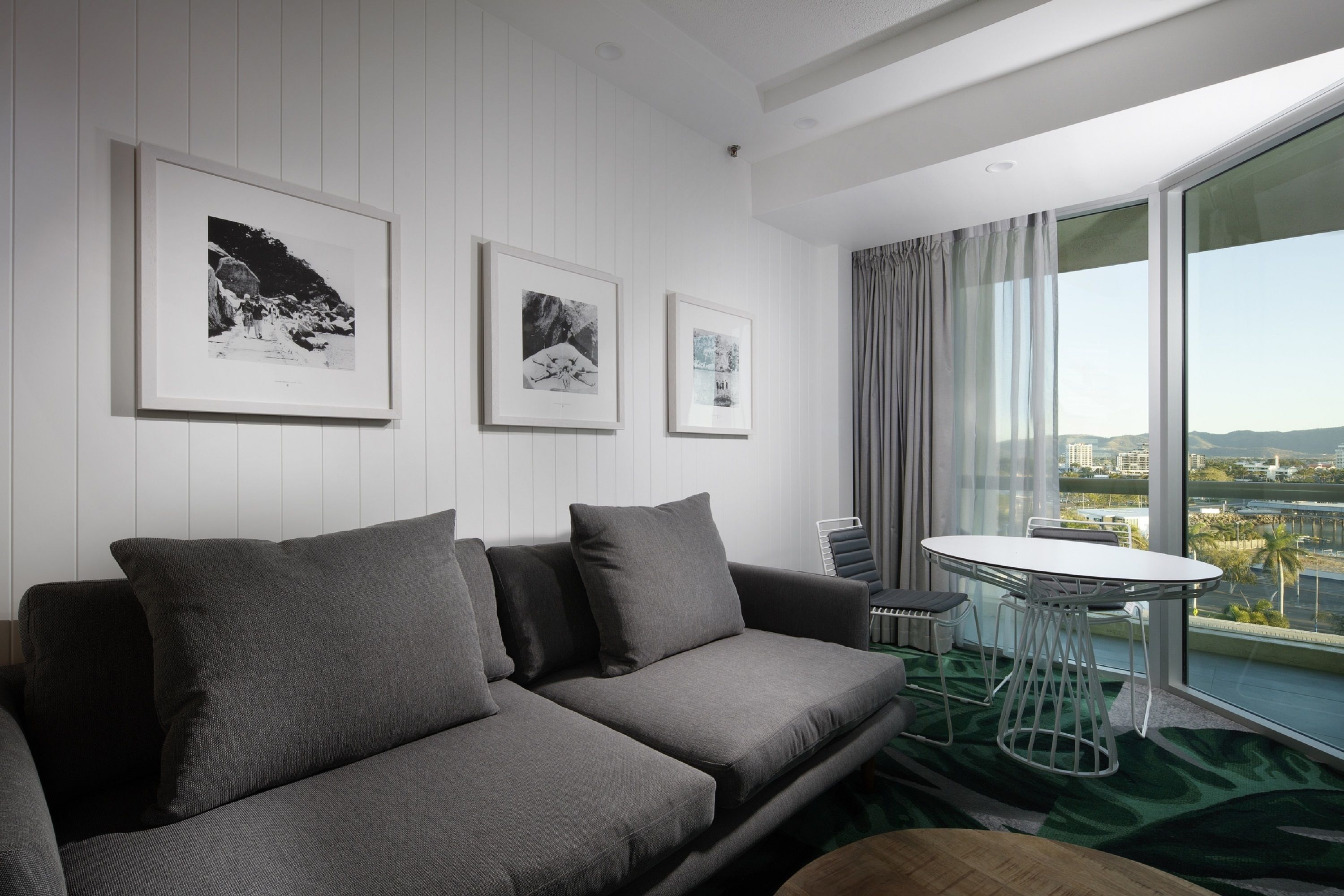 A modern living room with a grey sofa, a round table, and three framed pictures on the wall.