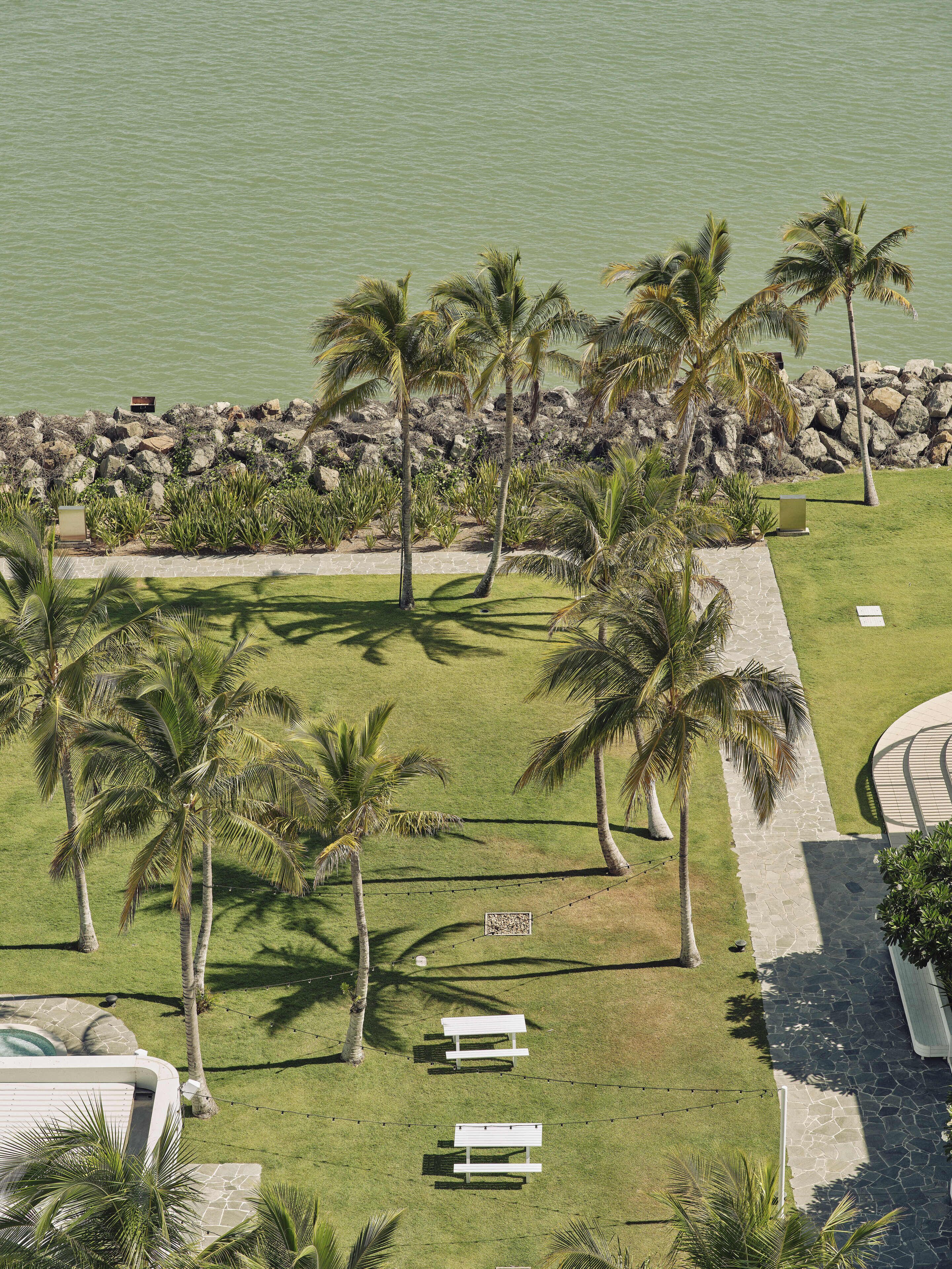 An aerial view of a resort with palm trees, a pool, and a stone pathway.