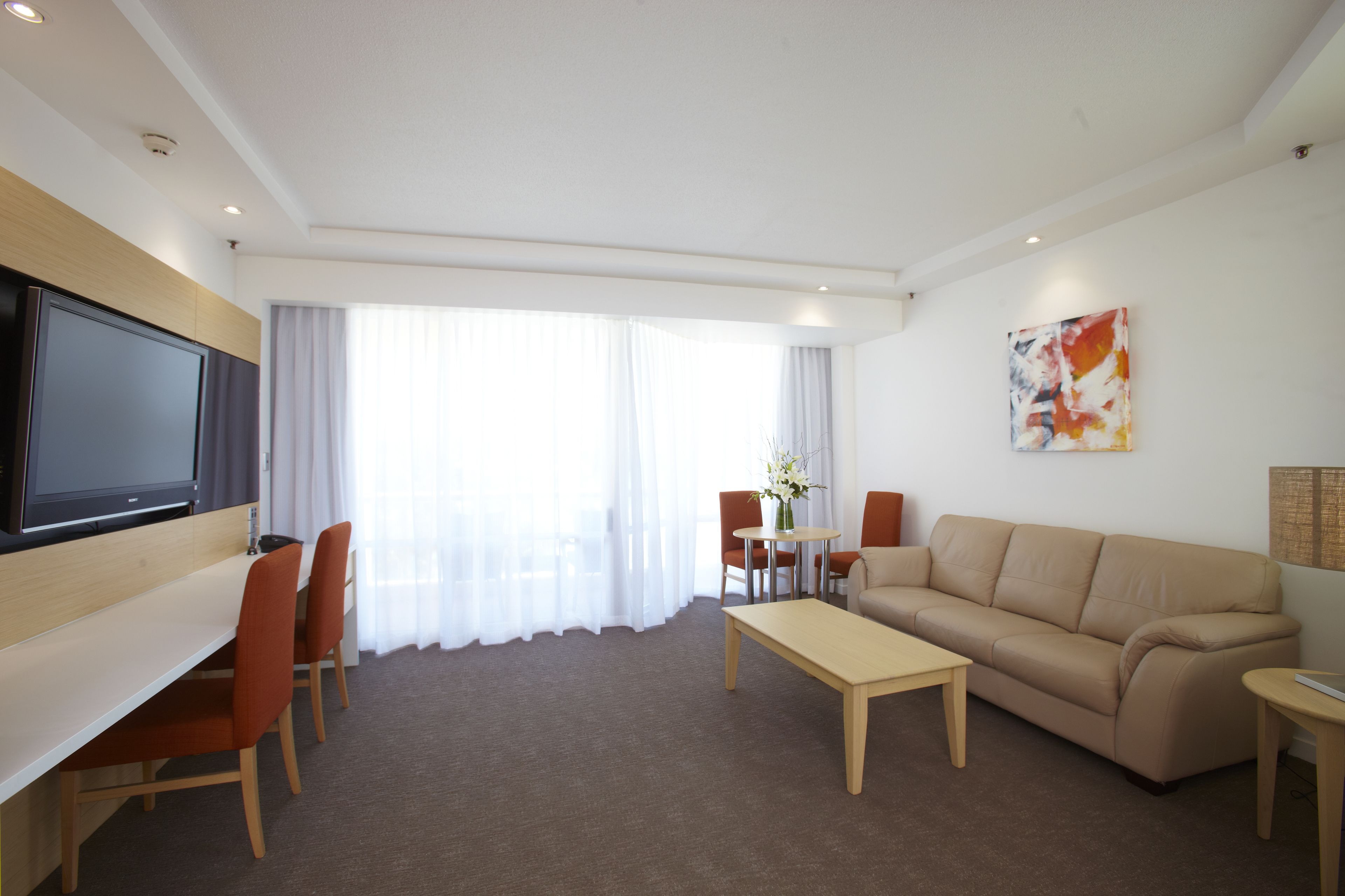 Une chambre d’hôtel moderne équipée d’un téléviseur à écran plat, d’un canapé, d’une table à manger et d’une table basse.