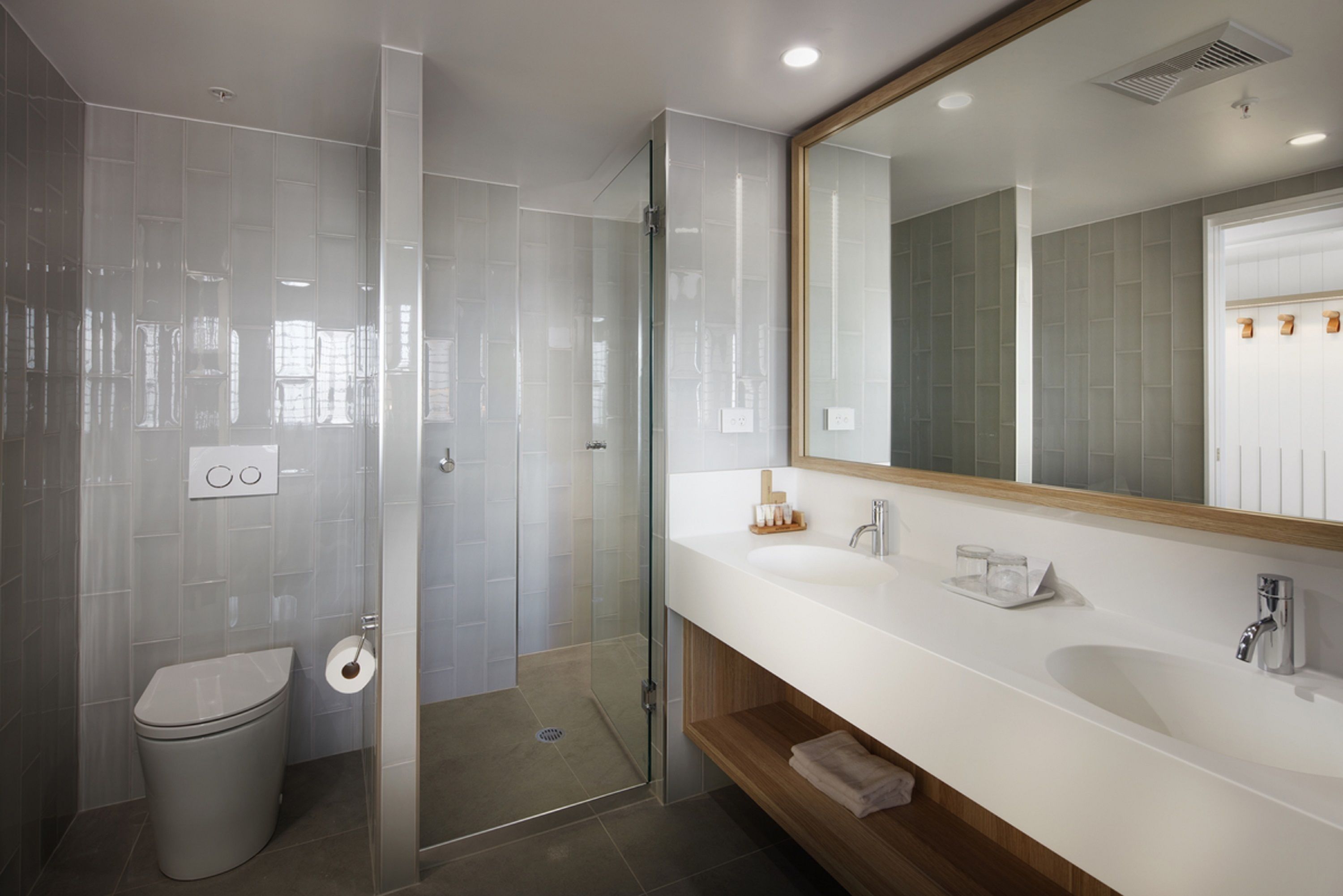 A modern bathroom with a glass shower enclosure, a white sink, and a large mirror.