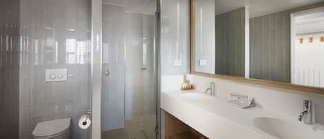 A modern bathroom with a glass shower enclosure, a white sink, and a large mirror.