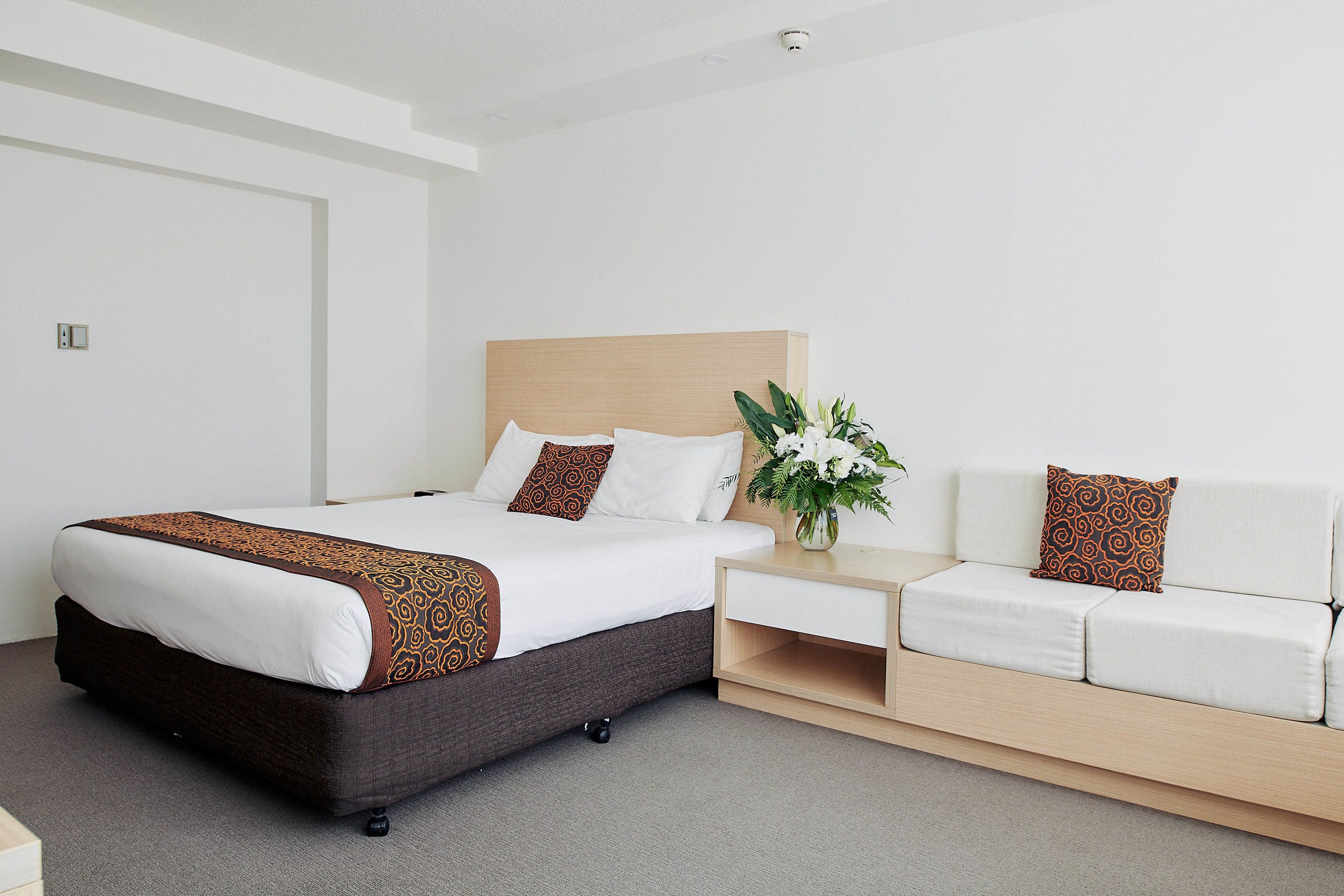 A hotel room with a bed, a sofa, and a nightstand.