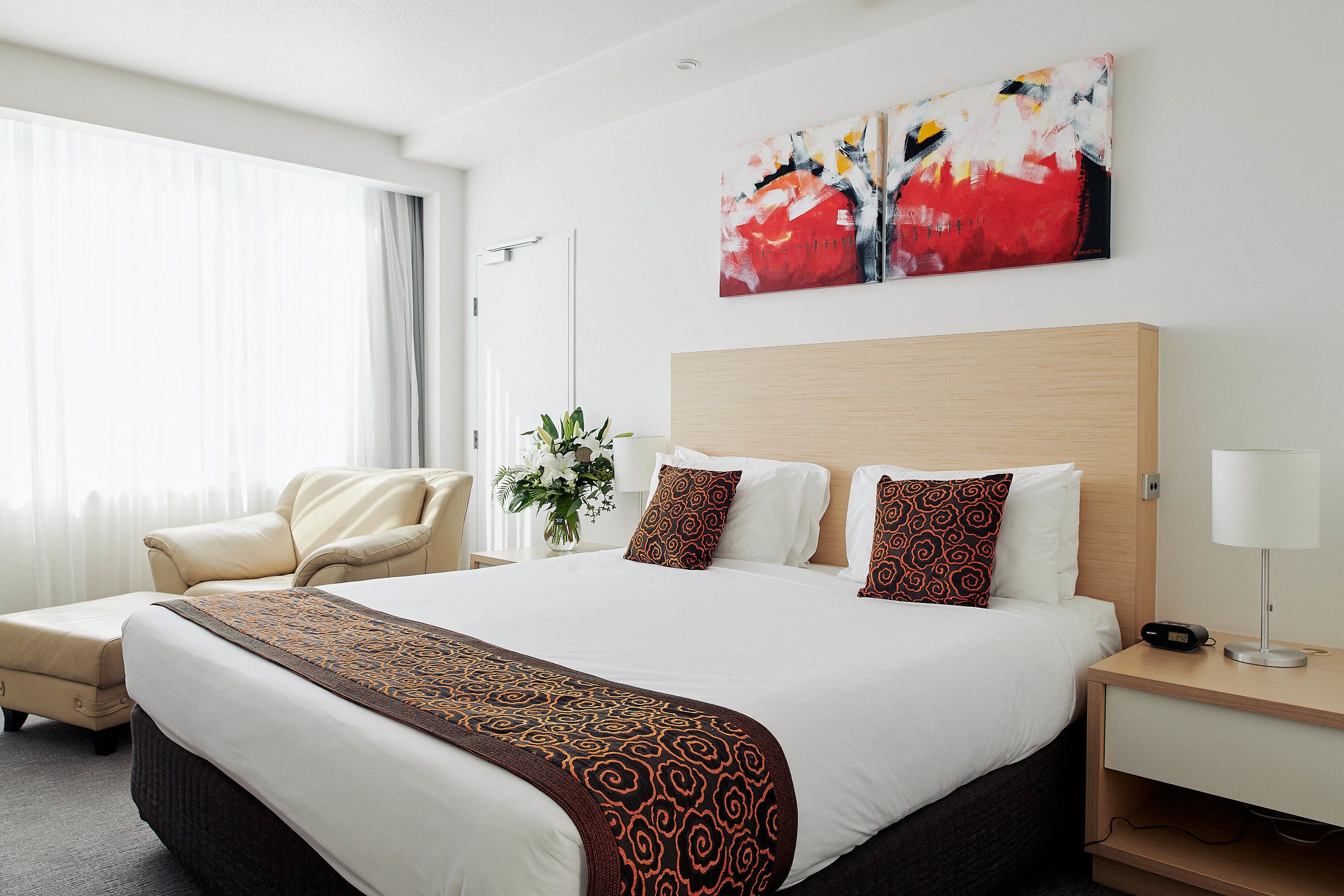 Une chambre d’hôtel avec un grand lit, une chaise, une table de chevet et un tableau au mur.
