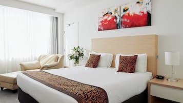 Une chambre d’hôtel avec un grand lit, une chaise, une table de chevet et un tableau au mur.