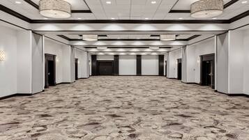 A spacious, well-lit hallway with a patterned carpet, multiple doors, and hanging light fixtures.