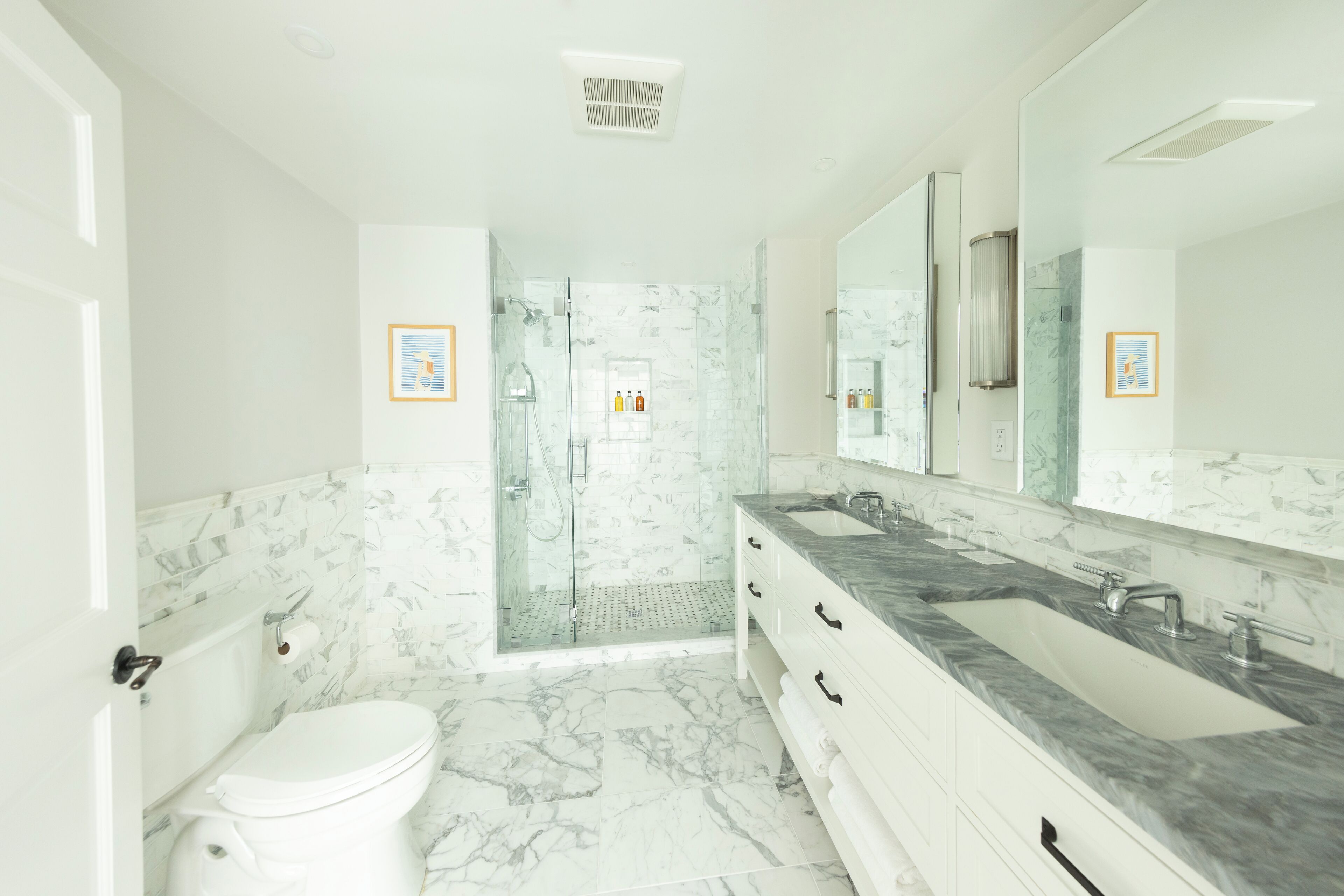 Une salle de bain moderne avec une douche à parois de verre, des toilettes blanches et un sol carrelé en marbre.