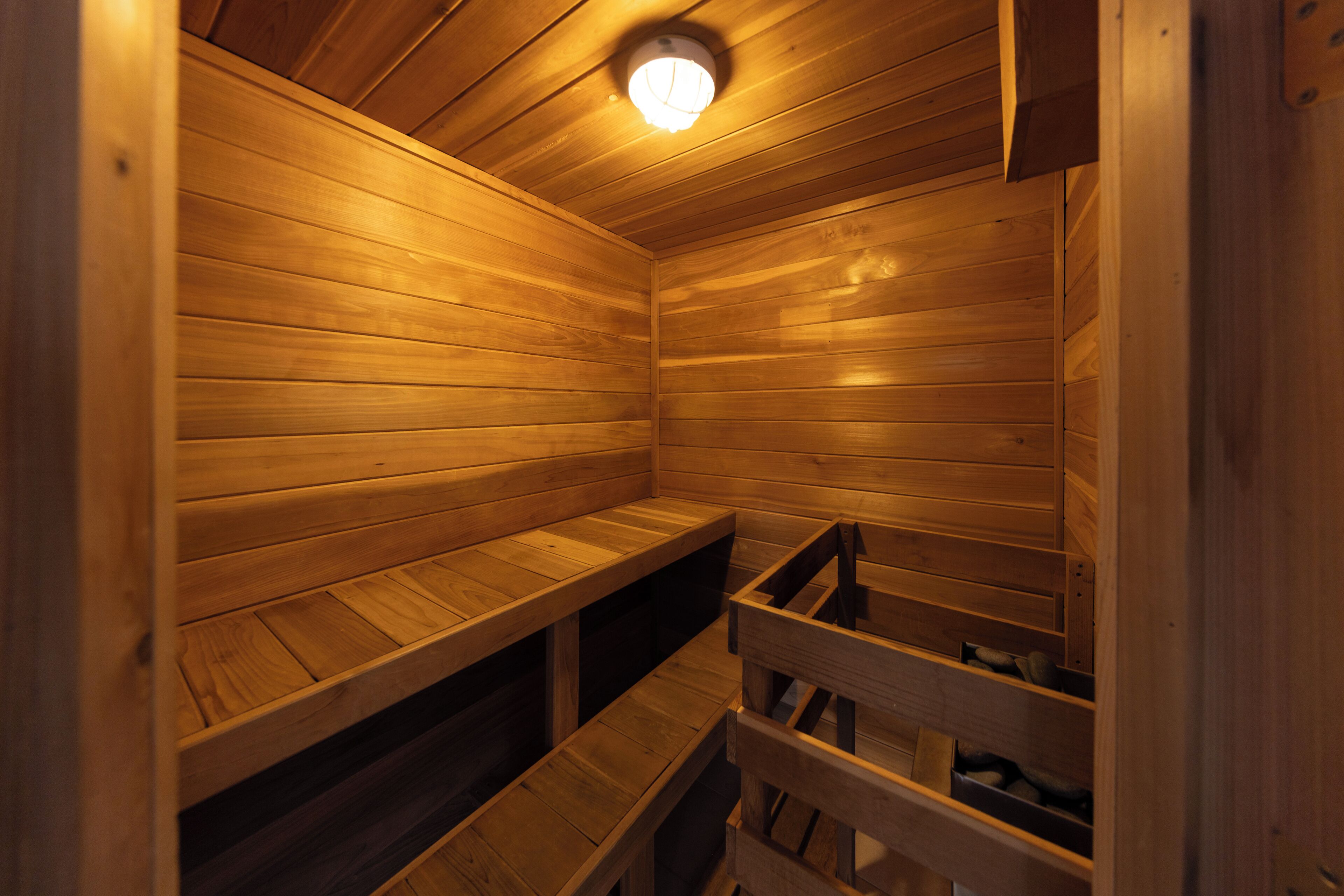 A wooden sauna with benches and a ceiling light.