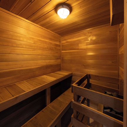 A wooden sauna with benches and a ceiling light.
