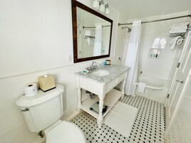 Un baño con inodoro, lavamanos, espejo y ducha.