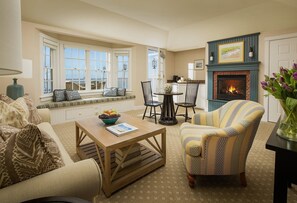 A cozy living room with a fireplace, a dining area, and a view of the outside.