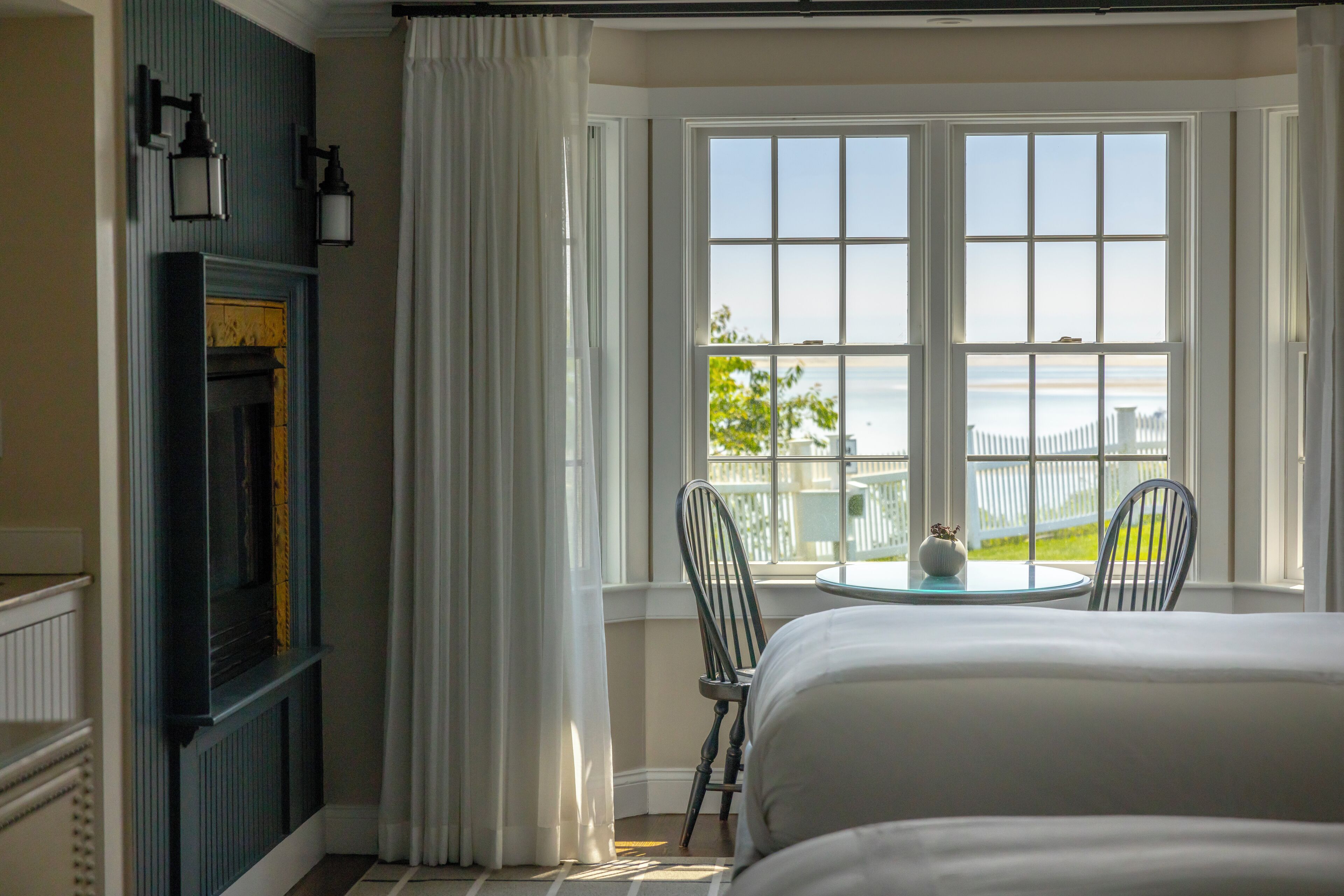 A room with a large window, a fireplace, and a bed.