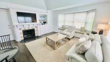 Un salon avec une cheminée, un canapé, une table basse et un téléviseur fixé au mur.