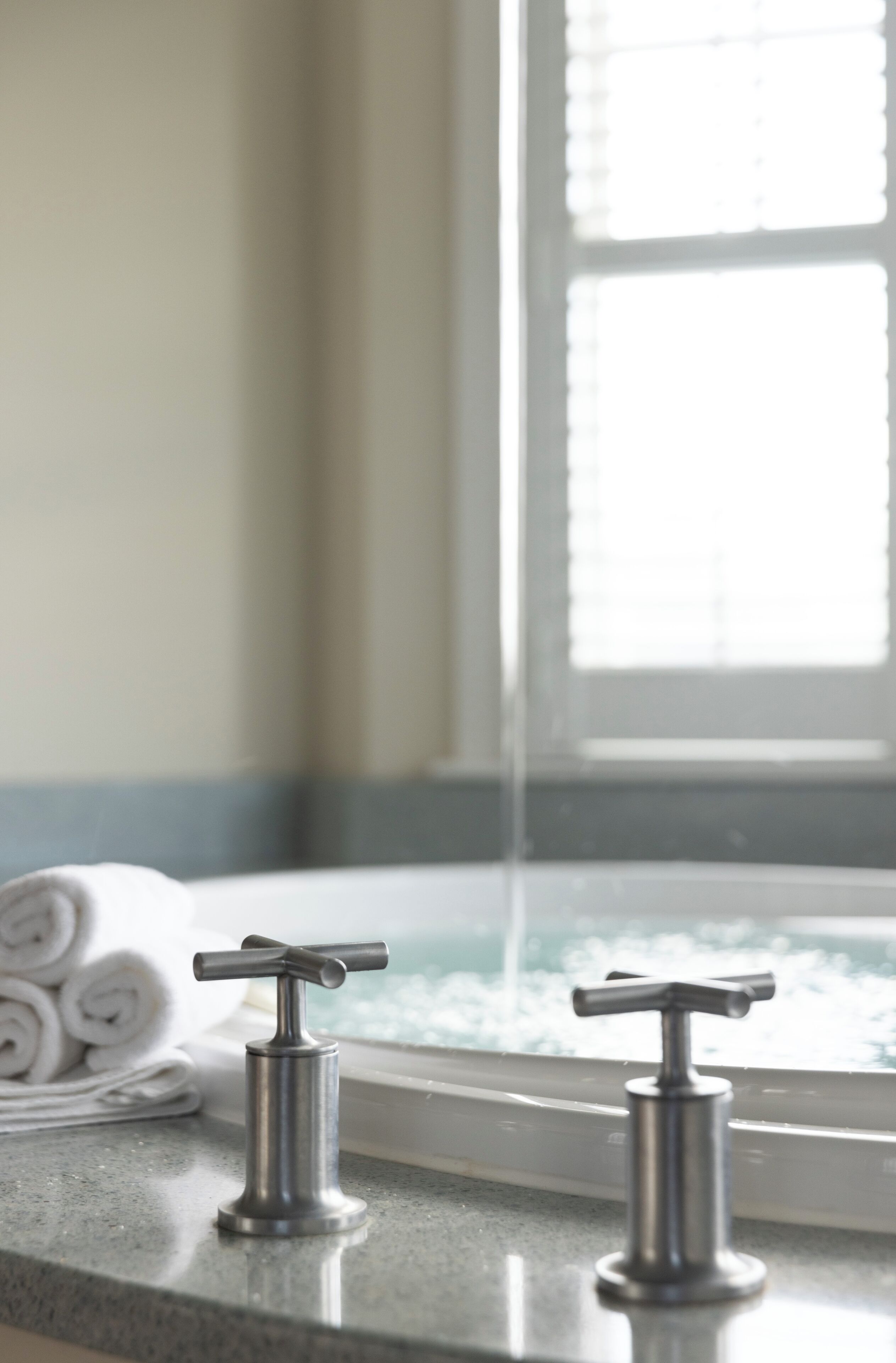 A bathroom with a modern faucet and a window with blinds.