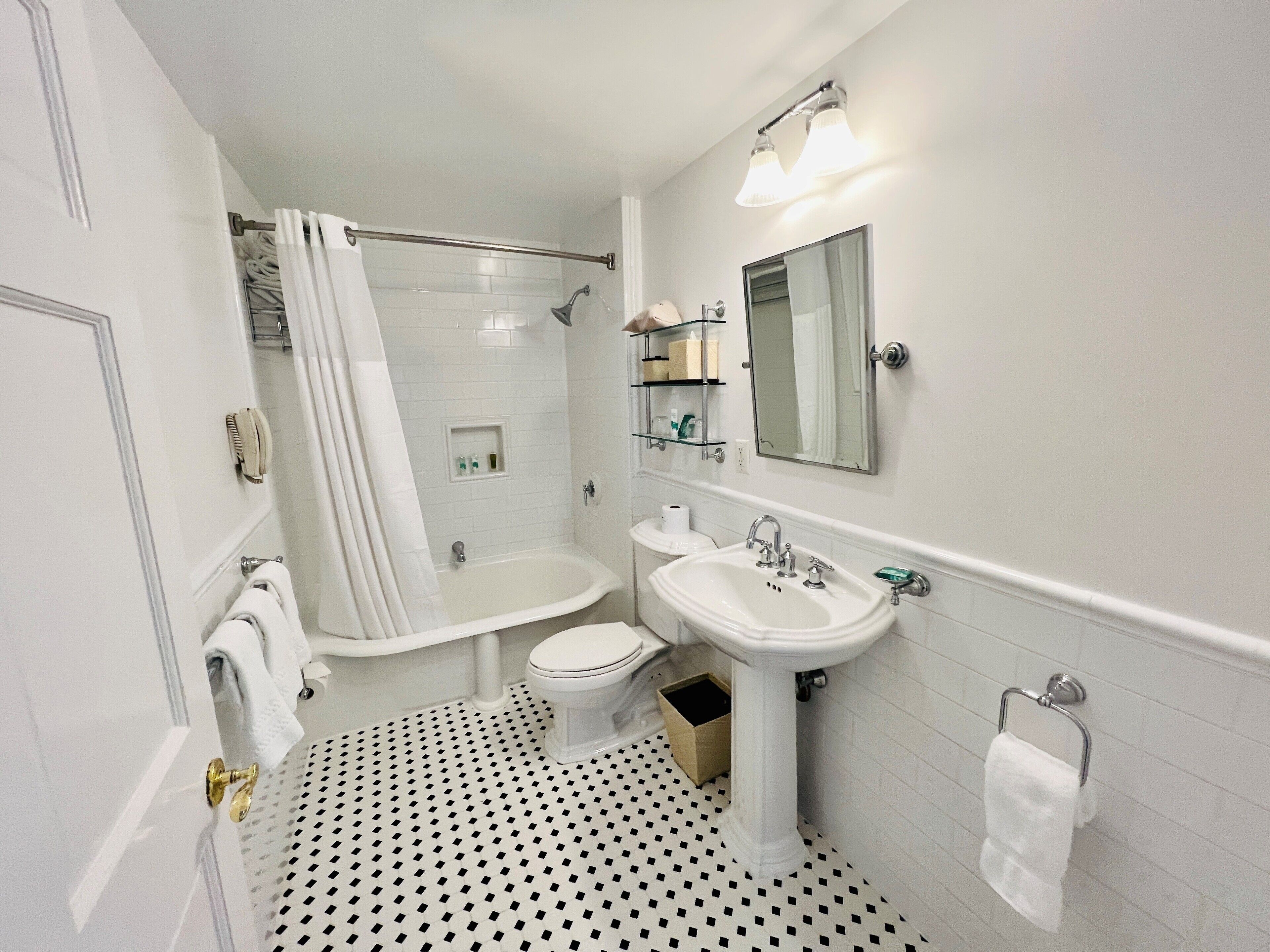 A bathroom with a bathtub, toilet, and sink, featuring a tiled floor and a mirror above the sink.