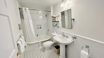 A bathroom with a bathtub, toilet, and sink, featuring a tiled floor and a mirror above the sink.