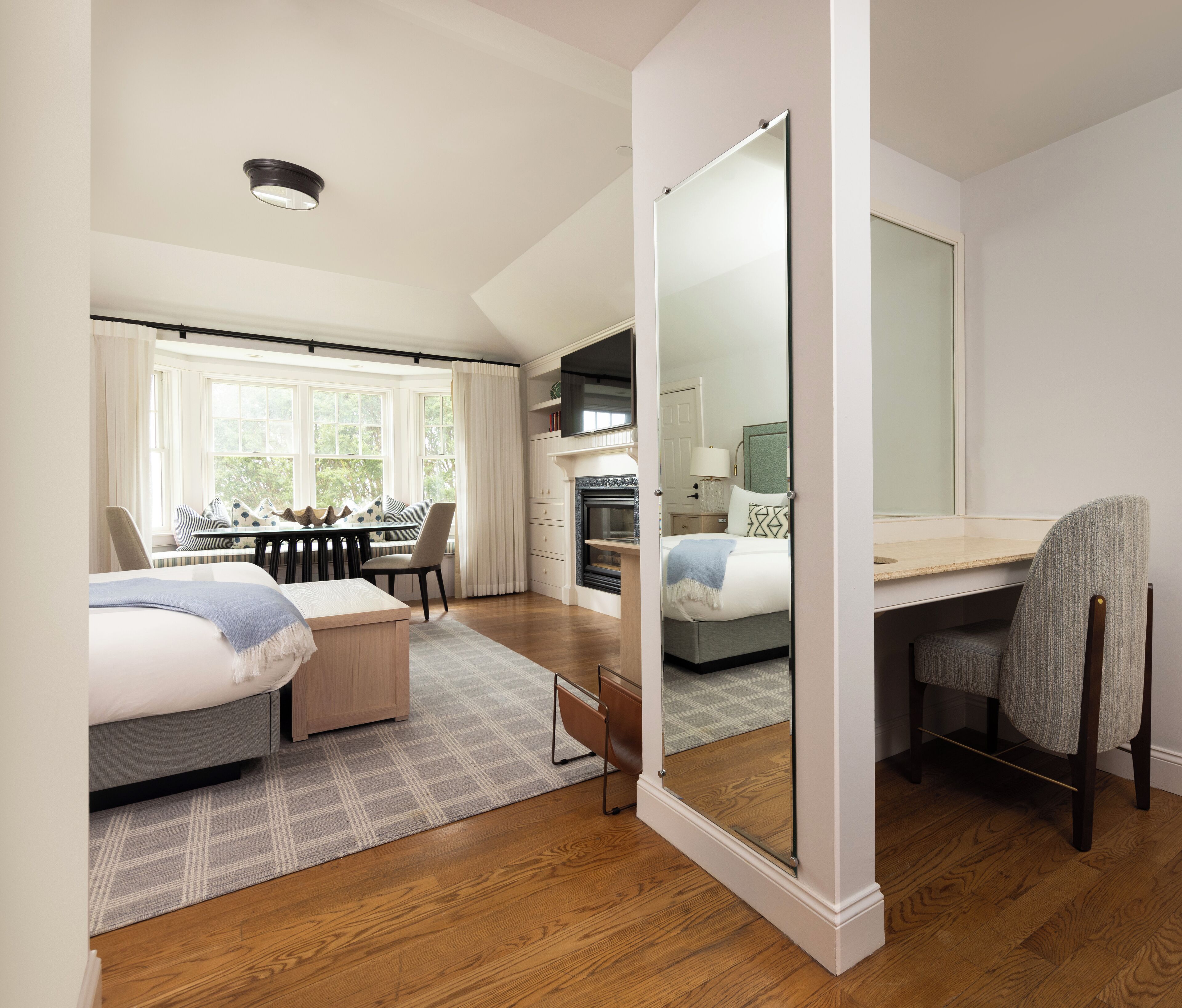 Quarto de hotel moderno com uma cama grande, uma escrivaninha, lareira e vista para o exterior.