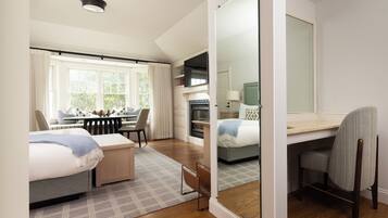 Quarto de hotel moderno com uma cama grande, uma escrivaninha, lareira e vista para o exterior.