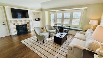 Un salon avec une cheminée, un téléviseur et un coin repas comprenant une table et des chaises.