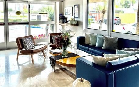 A modern lobby with a blue sofa, a wooden chair, a coffee table, and a decorative white pumpkin.
