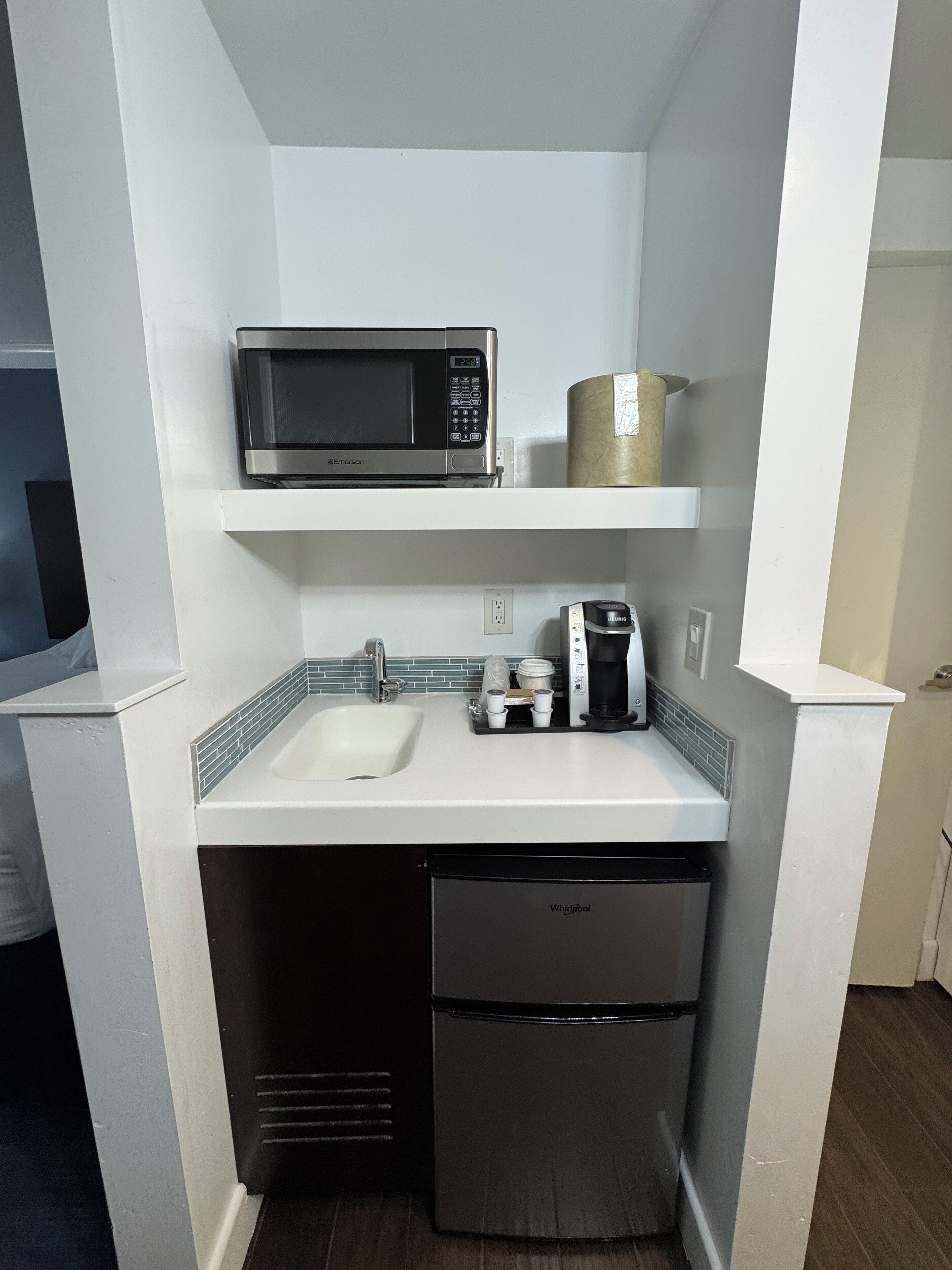 A compact kitchenette with a microwave, coffee maker, and dishwasher.