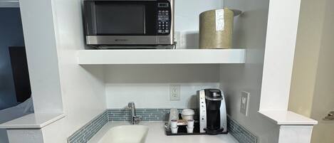 A compact kitchenette with a microwave, coffee maker, and dishwasher.