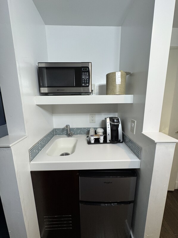 A compact kitchen with a built-in microwave, coffee maker, and dishwasher. - The Pacific Inn (Seal Beach)