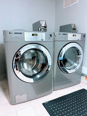 Two LG commercial washers in a laundry room with a black mat on the floor. - The Pacific Inn (Seal Beach)