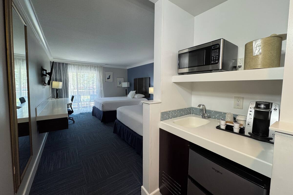 Une chambre d’hôtel avec un grand lit, un bureau, un four à micro-ondes, une machine à café et un lavabo.