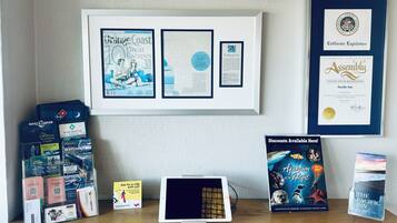A desk with travel brochures, a tablet, and a framed certificate of recognition.