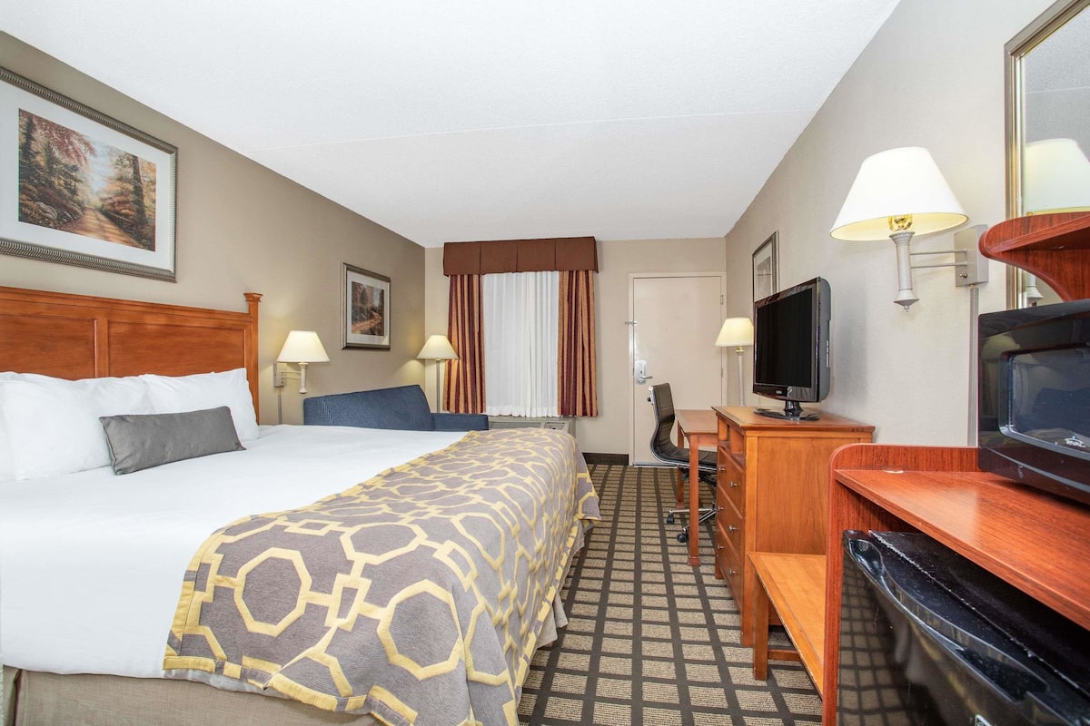 Een hotelkamer met een bed, een bureau, een televisie en een raam met gordijnen.