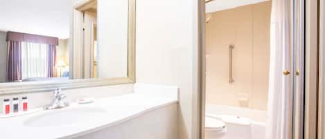 A modern bathroom with a white sink, mirror, and shower area.