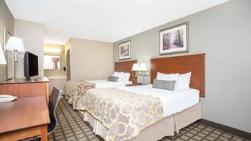 A hotel room with two beds, a desk, and a TV.