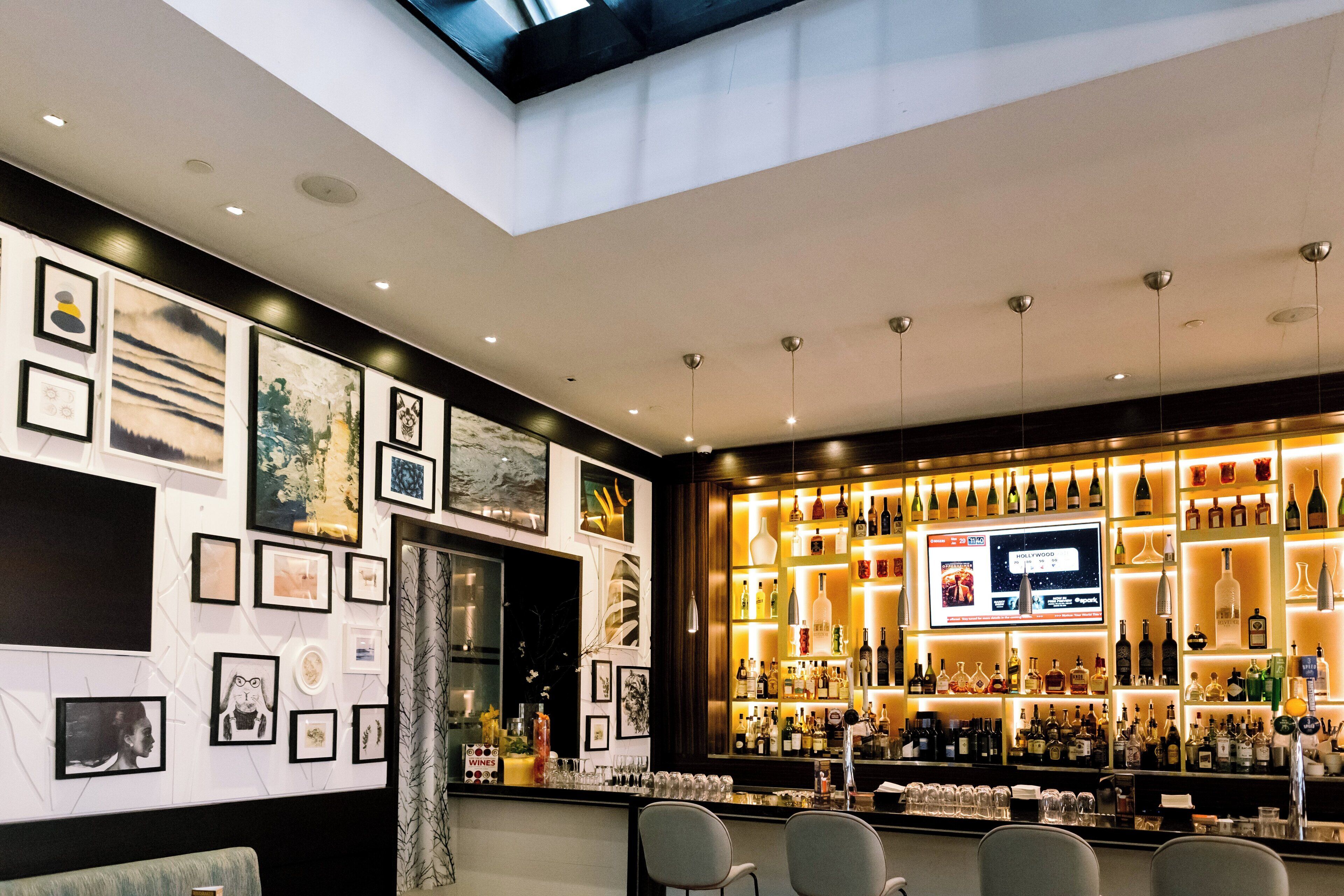 A bar area with a variety of liquor bottles, framed artwork on the walls, and seating.
